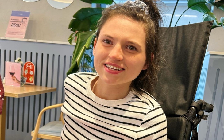 Młoda kobieta w koszulce w paski, uśmiechająca się w kawiarni.