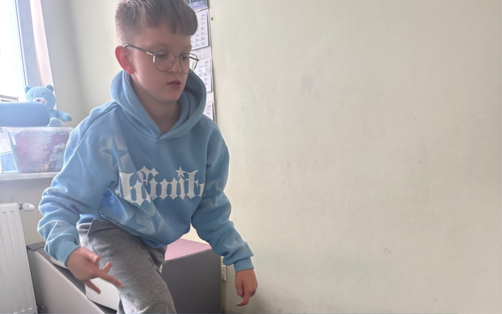 Chłopiec w błękitnej bluzie skacze w pokoju