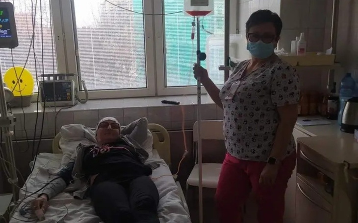 Osoba w szpitalu z opiekunem, w tle okno.