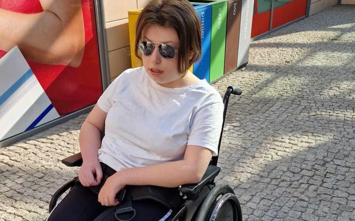 Młoda kobieta w okularach przeciwsłonecznych na wózku inwalidzkim.