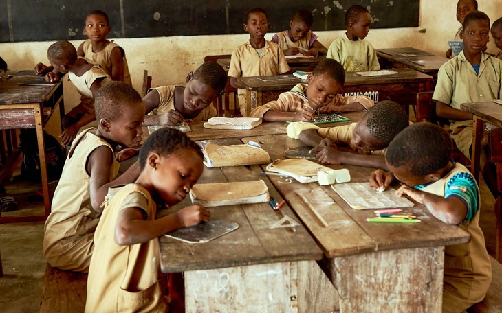 Dzieci w klasie, skupione na nauce i rysowaniu.