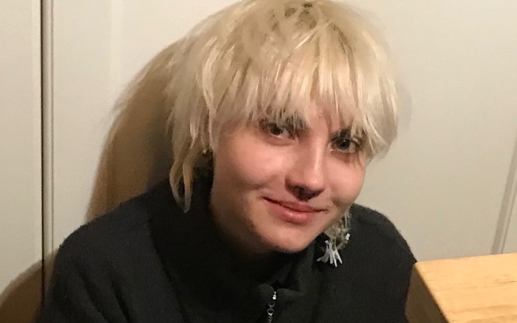 Młoda osoba z jasnymi włosami, uśmiechająca się do kamery.