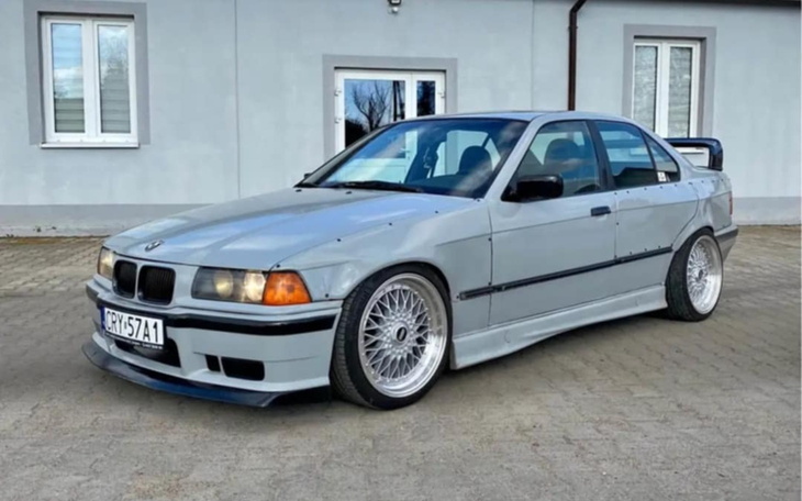 Szary samochód BMW zaparkowany przed budynkiem.