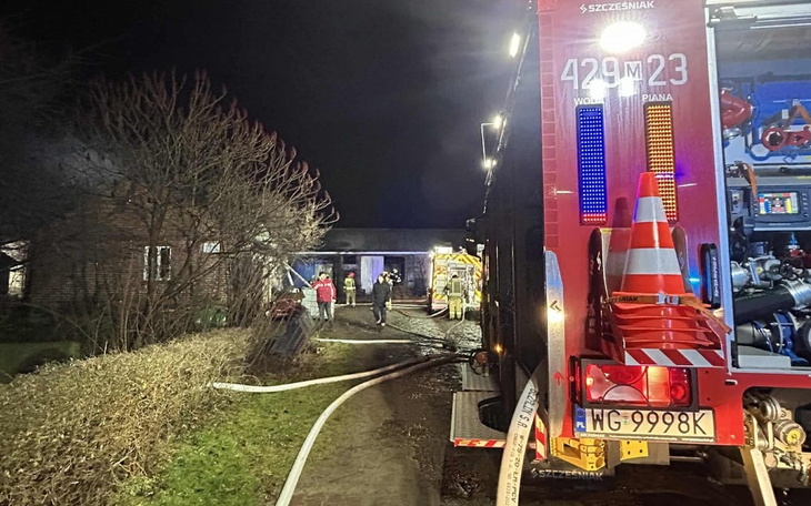 Akcja gaśnicza w nocy, strażacy przy budynku.