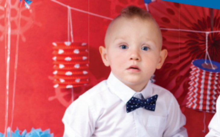 Mały chłopiec w eleganckim stroju, zaskoczony na zdjęciu.