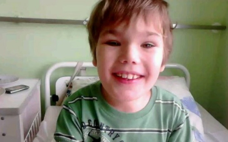 Chłopiec w łóżku szpitalnym, uśmiechający się do kamery.