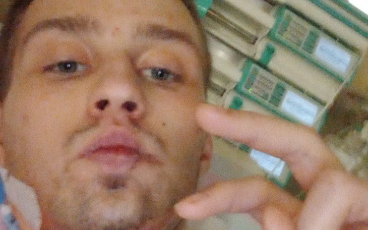 Mężczyzna leżący w szpitalu, pokazujący znak pokoju.