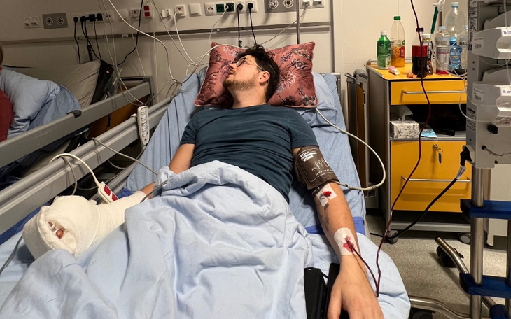 Mężczyzna leżący w szpitalnym łóżku z opatrunkami.