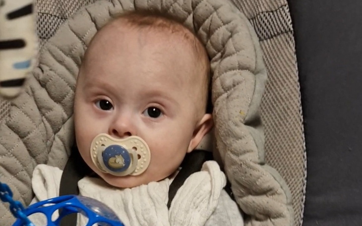 Niemowlę w foteliku, z zabawką w ręku.