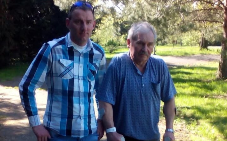 Mężczyzna wspiera starszego pana podczas spaceru w parku.