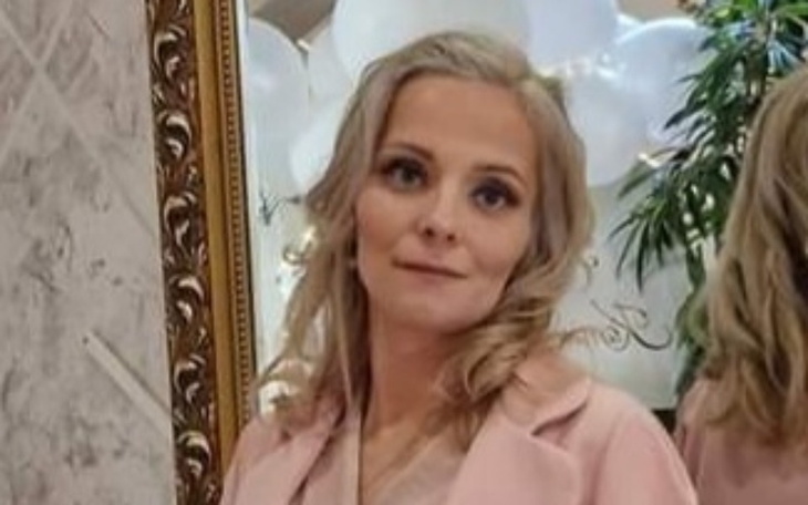 Kobieta w eleganckim ubraniu, pozująca przed lustrem.