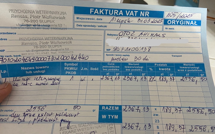 Faktura VAT z danymi i kwotami, trzymana w ręku.