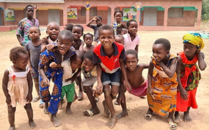 Grupa dzieci bawiących się na podwórku, uśmiechniętych i radosnych.