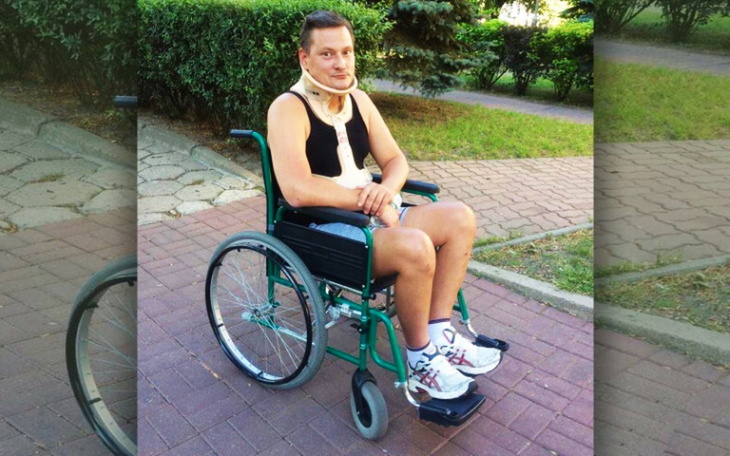 Mężczyzna na wózku inwalidzkim, uśmiechający się na spacerze.