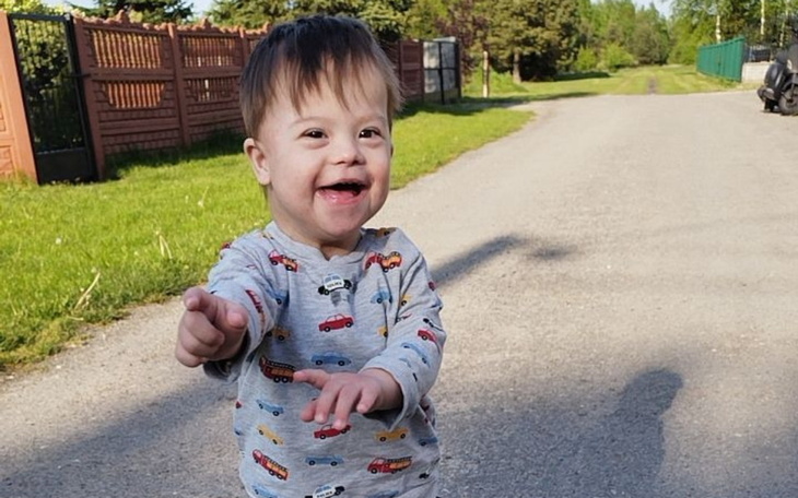 Mały chłopiec bawiący się na drodze, uśmiechnięty i szczęśliwy.