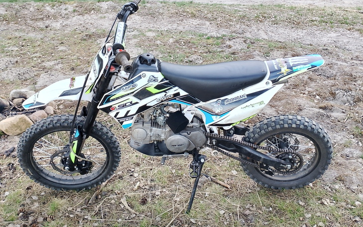 Motocykl terenowy na trawie, gotowy do jazdy.