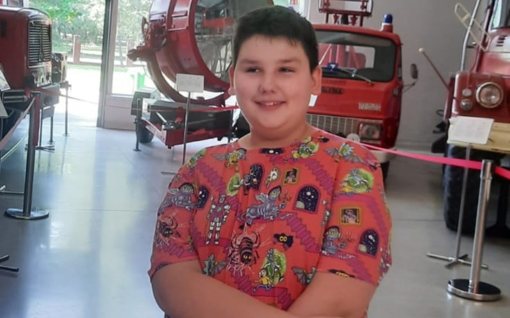 Chłopiec w kolorowej koszulce w muzeum z pojazdami.