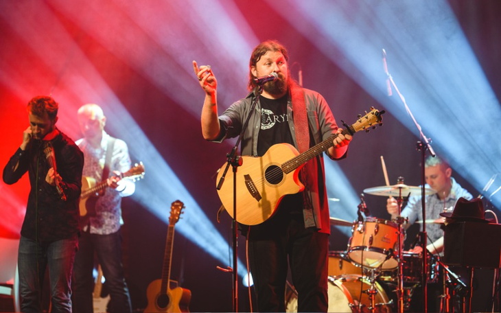 Muzyk grający na gitarze podczas koncertu z zespołem.