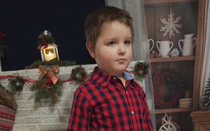 Chłopiec w czerwonej koszuli na tle dekoracji świątecznych.