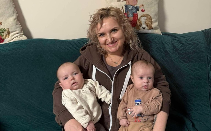 Kobieta z dwójką niemowląt na kanapie.