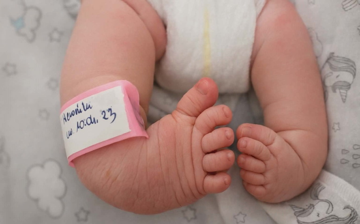 Noworodek z opaską na ręce, śpi w łóżeczku.