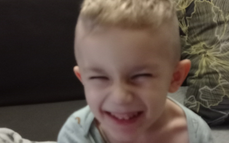 Chłopiec z szerokim uśmiechem, bawiący się.