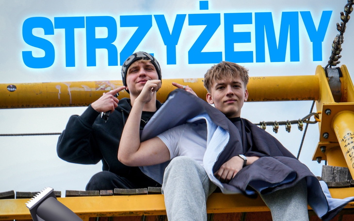 Młodzi mężczyźni w trakcie strzyżenia, z uśmiechami na twarzach.