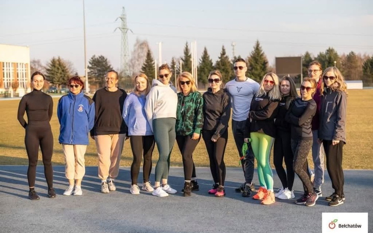 Grupa osób na boisku, gotowych do treningu na świeżym powietrzu.
