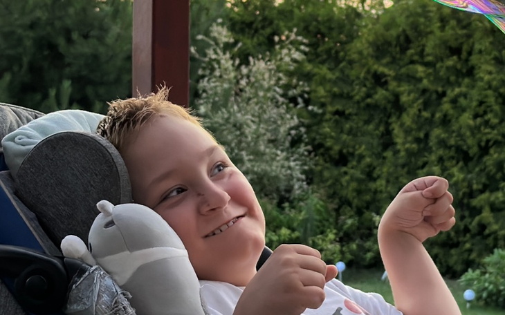 Chłopiec relaksujący się na tarasie, uśmiechnięty i zadowolony.