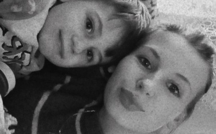 Dziecko i dorosła osoba leżą razem, uśmiechając się do kamery.