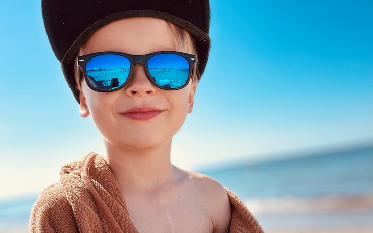 Chłopiec w okularach przeciwsłonecznych, na plaży.