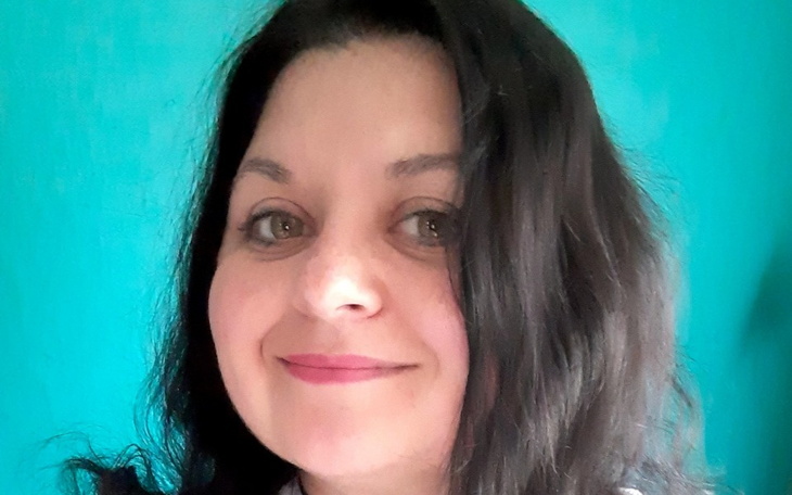 Kobieta z długimi włosami, uśmiechająca się do kamery.