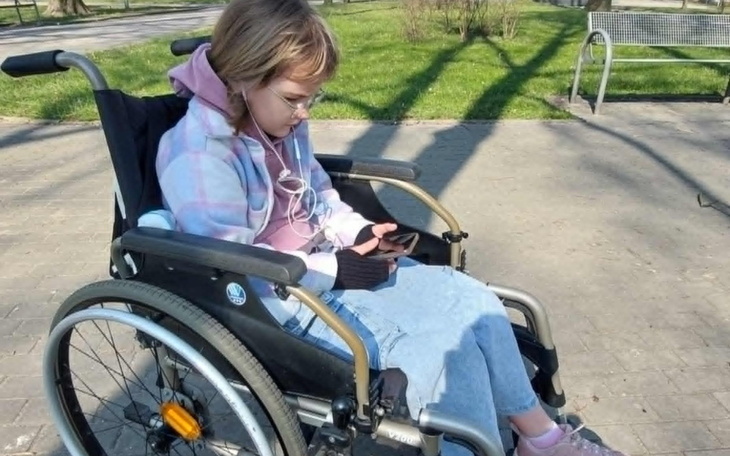 Dziewczynka w wózku inwalidzkim korzystająca z telefonu.