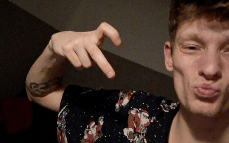 Mężczyzna w koszulce z motywem świątecznym, robiący gest pokoju.