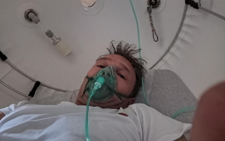 Osoba w szpitalu z maską tlenową na twarzy.