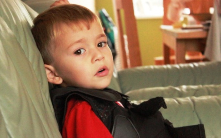 Chłopiec w czerwonym t-shircie, siedzący na kanapie.