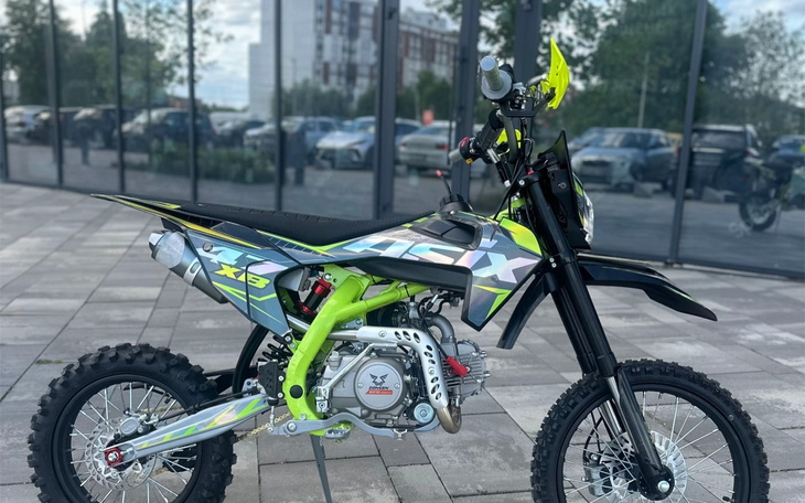 Motocykl terenowy w jaskrawych kolorach, zaparkowany na zewnątrz.