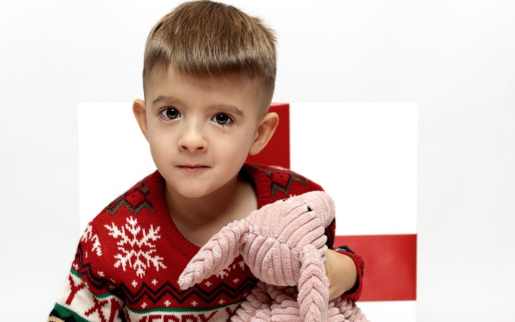 Chłopiec w swetrze z mikołajem trzyma różowego królika.