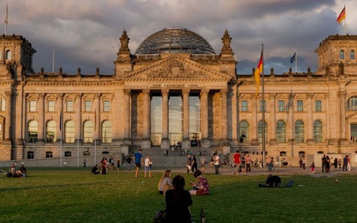Budynek Reichstagu w Berlinie, z ludźmi na trawie.