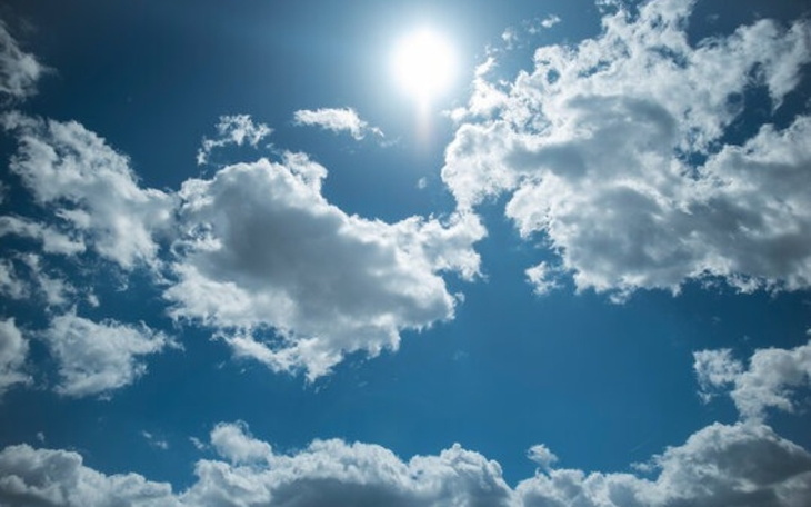 Błękitne niebo z białymi chmurami i jasnym słońcem.