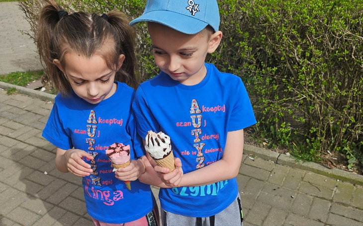 Dwoje dzieci trzymających lody na słonecznym spacerze.
