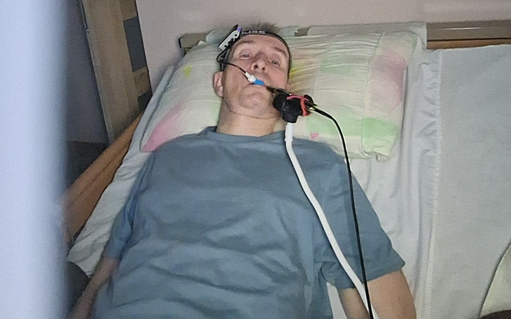 Mężczyzna leżący w łóżku z aparaturą medyczną.