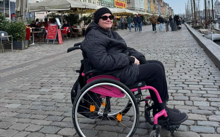 Osoba na wózku inwalidzkim na nadmorskiej promenadzie.
