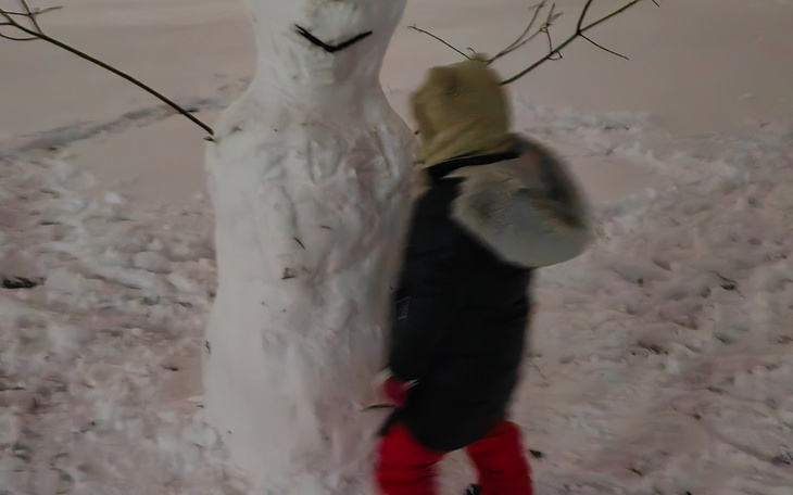 Dziecko bawiące się ze śnieżnym bałwanem w zimie.