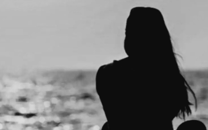 Silhouette kobiety siedzącej nad morzem.