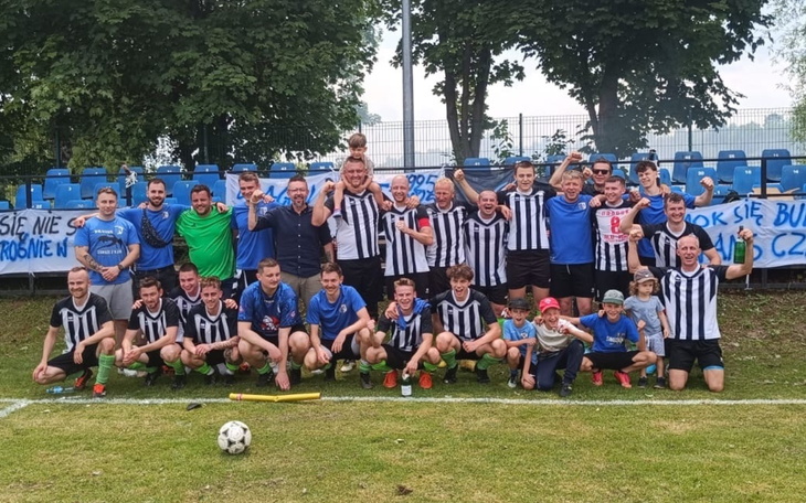 Grupa ludzi w strojach piłkarskich, świętujących zwycięstwo.