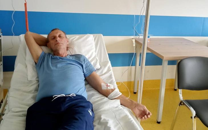 Mężczyzna leżący w szpitalnym łóżku, odpoczywający.