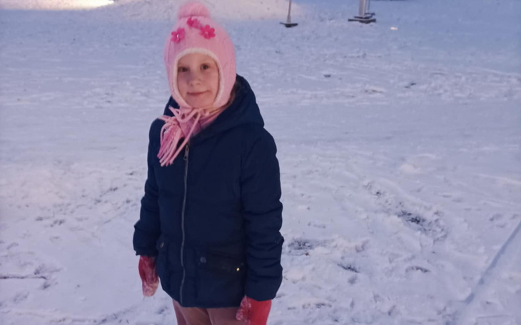 Dziewczynka w zimowym ubraniu, bawiąca się na śniegu.