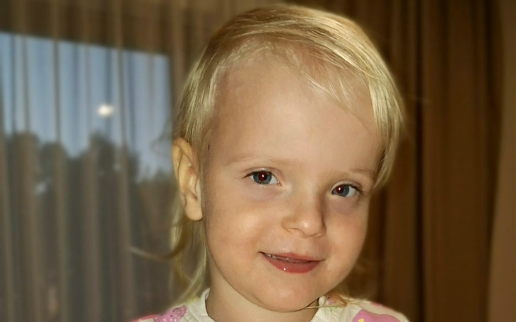 Uśmiechnięta dziewczynka z jasnymi włosami.