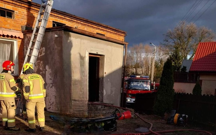 Strażacy przy budynku, przygotowujący się do akcji ratunkowej.
